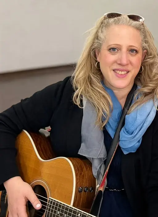 Yael, who performs as Yael Lerato, smiling with her acoustic guitar